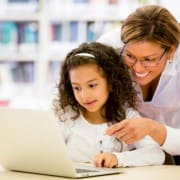 child and teacher on computer